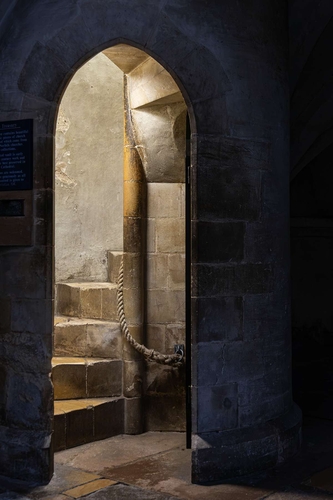 The old stone spiral staircase up to The Treasury in Norfolk Cathedral. The rope is stained with the sweat and grease…