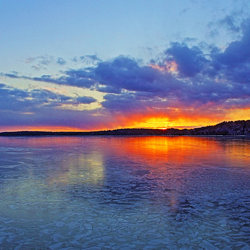 A glazed over Kennebecasis Bay reflects the hues of a late winter sunset in Rothesay, New Brunswick, Canada.