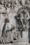 Façade, left portal relief, St. Rose of Lima before Lady of the Rosary