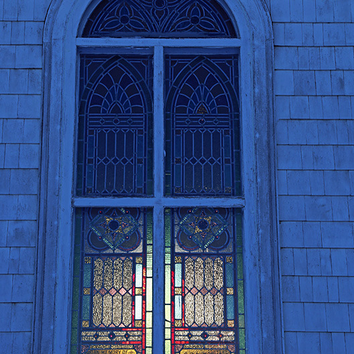 A stained glass window partially illuminated by the early morning sunlight.