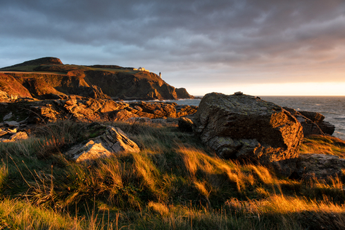 The first light of the day as the sun peeps over the horizon and bathes Maughold Head in golden light.