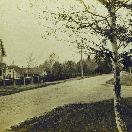An early street view of Rothesay, New Brunswick, Canada & showing a road intersection, the Netherwood Gate, and lady…