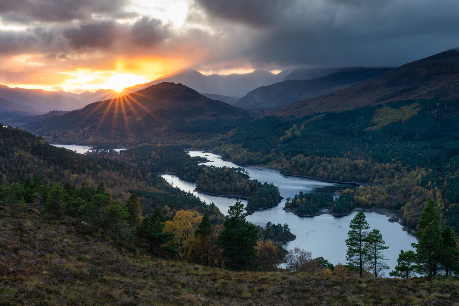 The sun setting behind the mountain Beinn a Mheadhoin, with loch Beinn a Mheadhoin in front. 2019