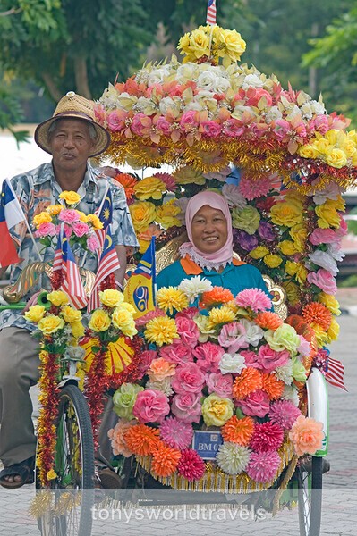 Happy smiling couple in a Colourful floral rickshaw, Melaka, Malaysia - Smiling faces of the World