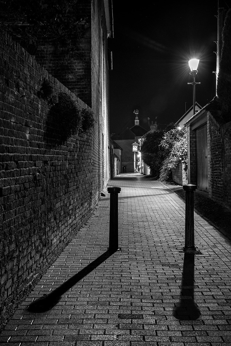 Bollards and shadow in an alleyway at night