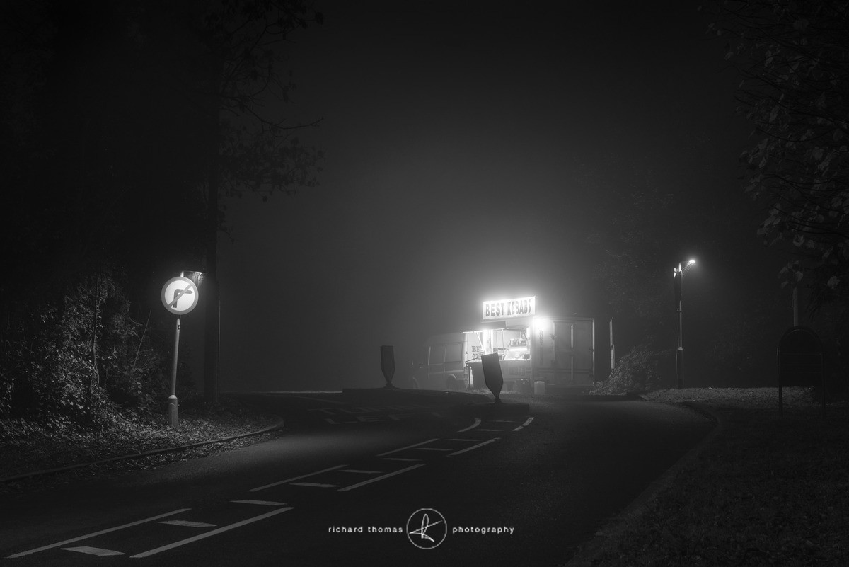 A Kebab van on the side of a road on a foggy night