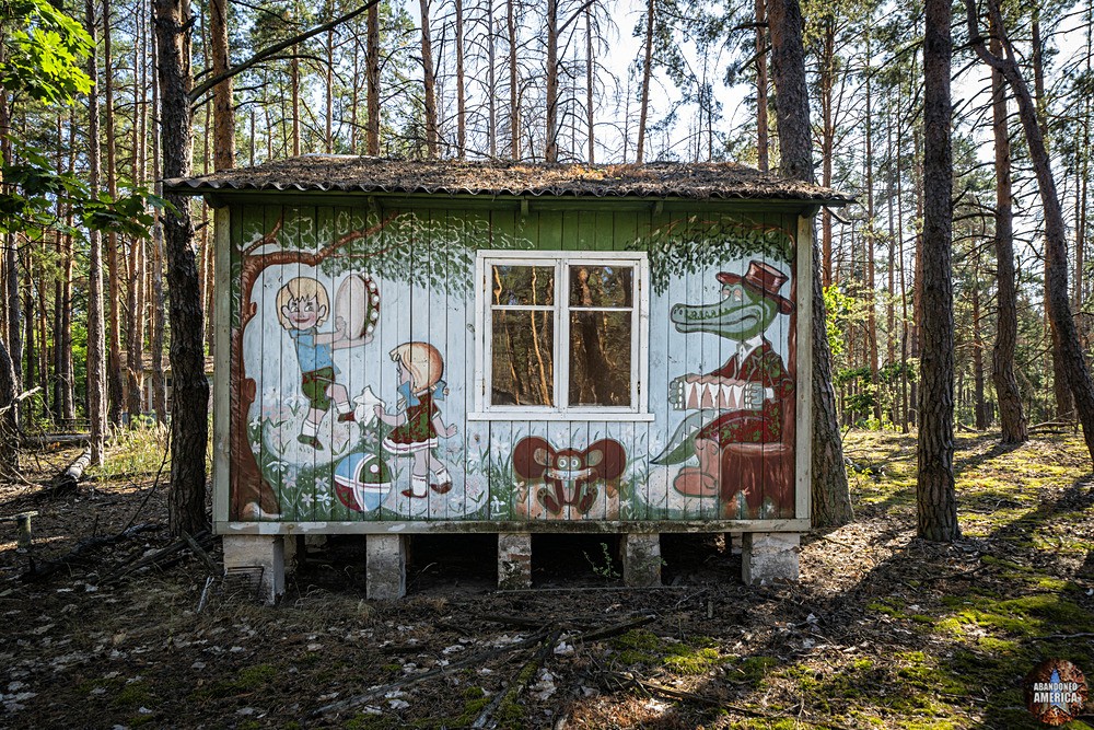 A cabin with children playing watched by a cartoon alligator