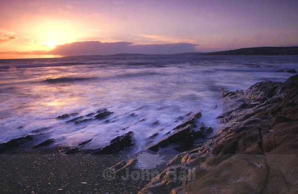 waves crashing on shoreline at sunset, garrettstown, co. cork, ireland.