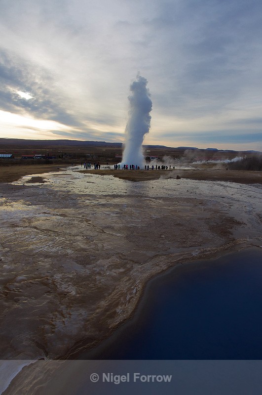 Strokkur erupts, Blesi hot water pools in the foreground - Iceland