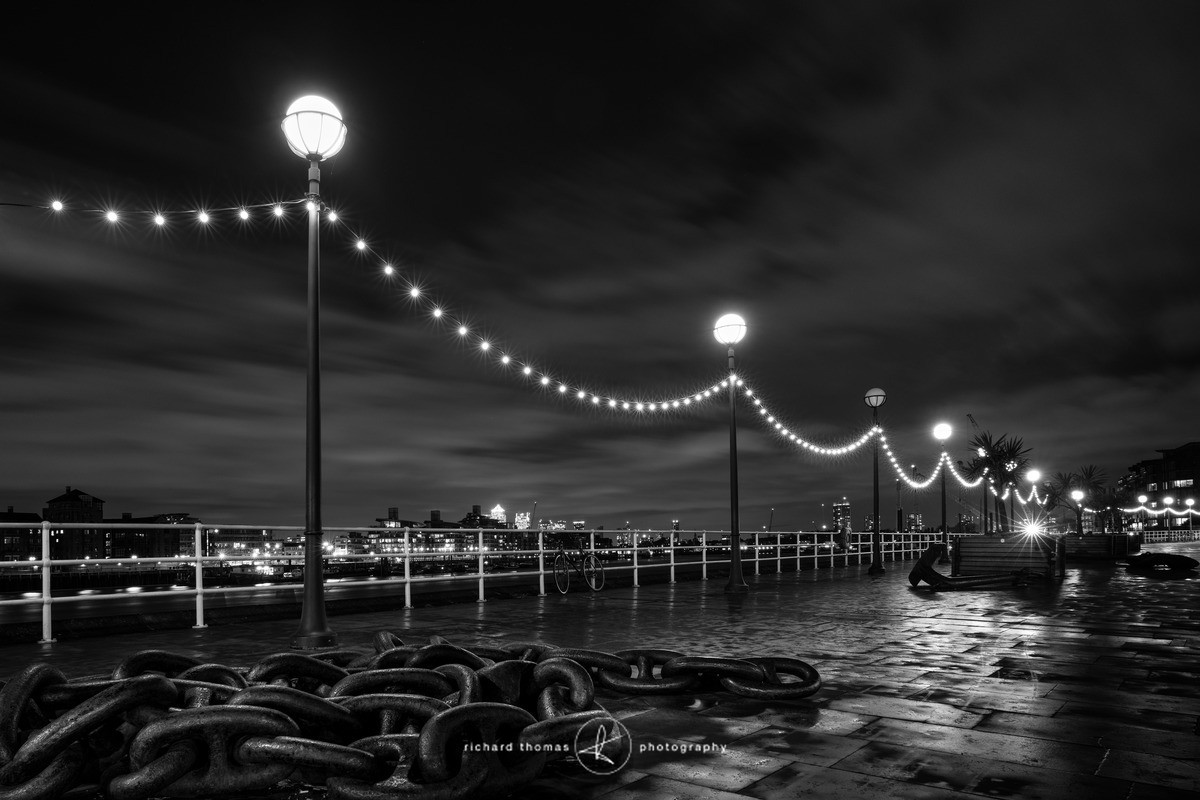 Butlers Wharf on the London south bank looking towards Canary wharf across the river Thames at night