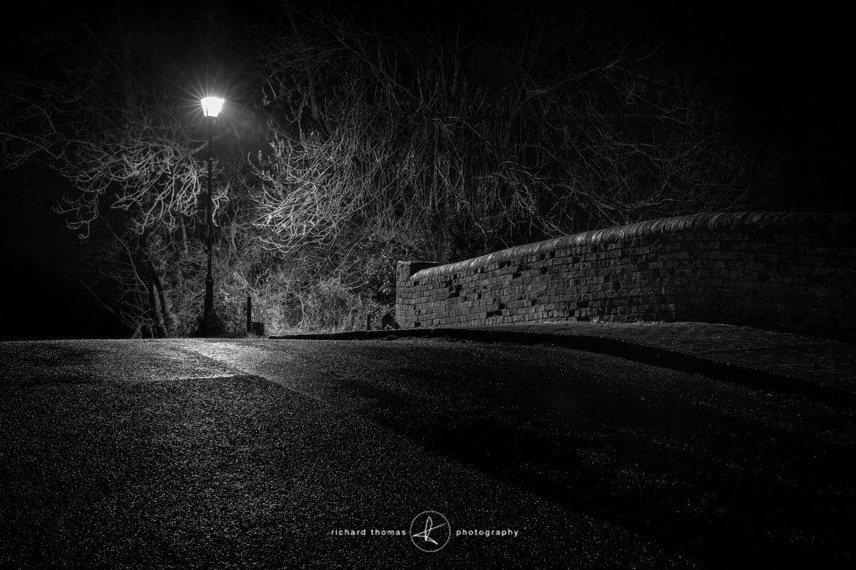 A street lamp illuminating a bridge over the Basingstoke canal at night