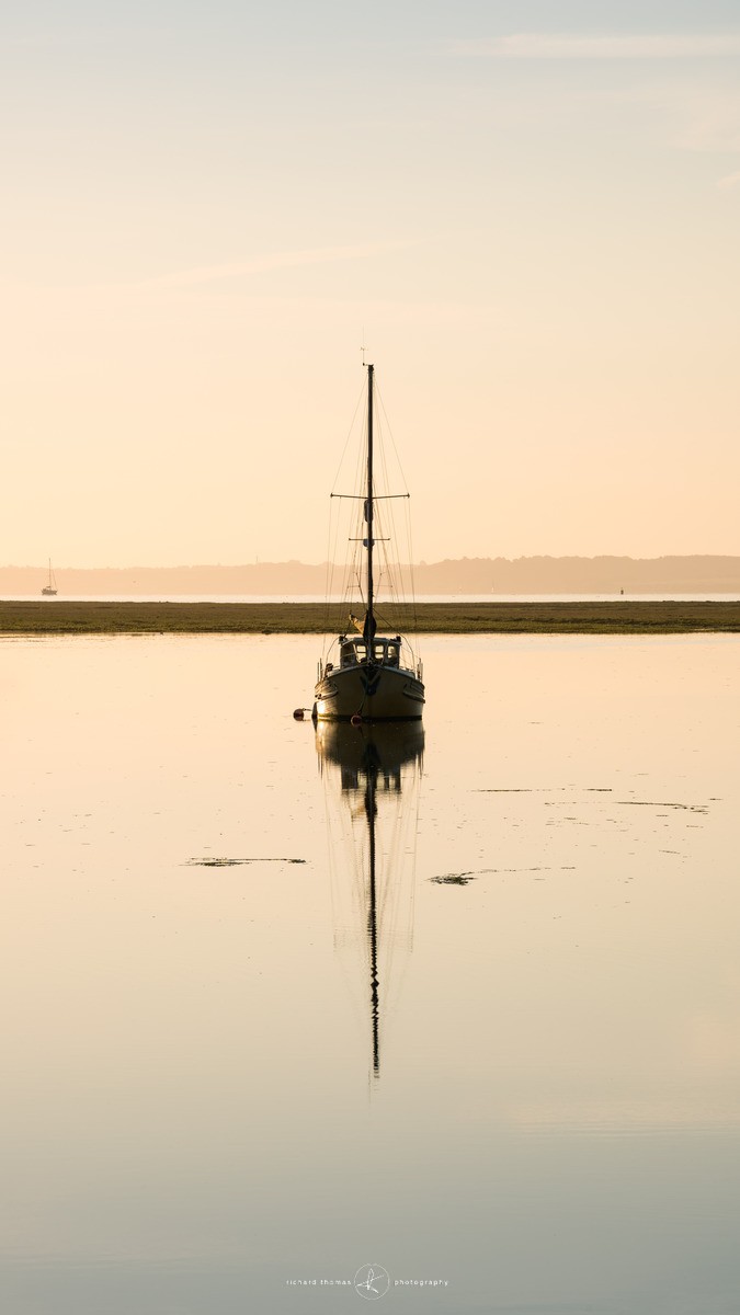 A yacht anchored in the Solent near Lymington harbour just after dawn on a summer morning