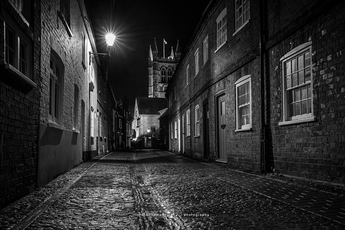 Cobbled street with St Andrews church at the end at night